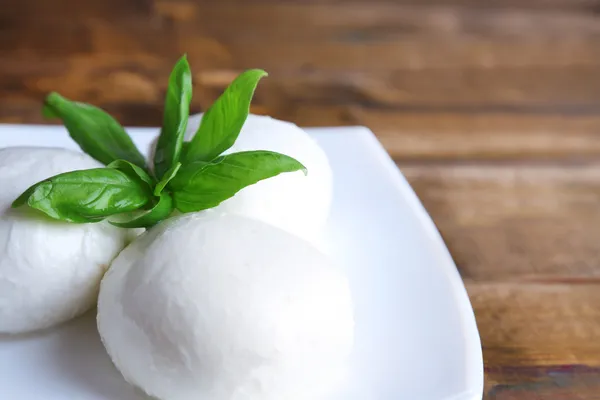 Lezzetli mozzarella peyniri Fesleğenli ahşap zemin üzerinde plaka üzerinde — Stok fotoğraf