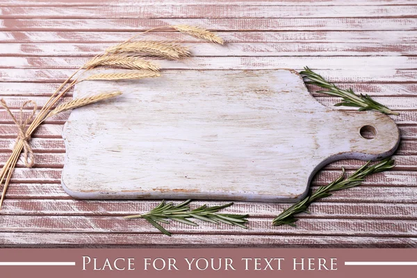 Wheat ears, rosemary and cutting board on wooden table — Stock Photo, Image