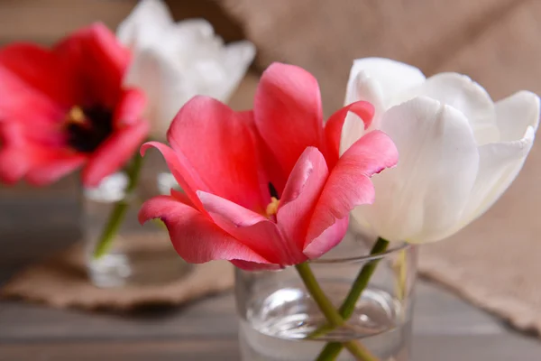 Hermosos tulipanes en cubo en jarrón sobre mesa sobre fondo gris —  Fotos de Stock