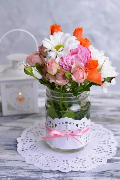 Beautiful bouquet of bright flowers in jar on table on grey background — Stock Photo, Image