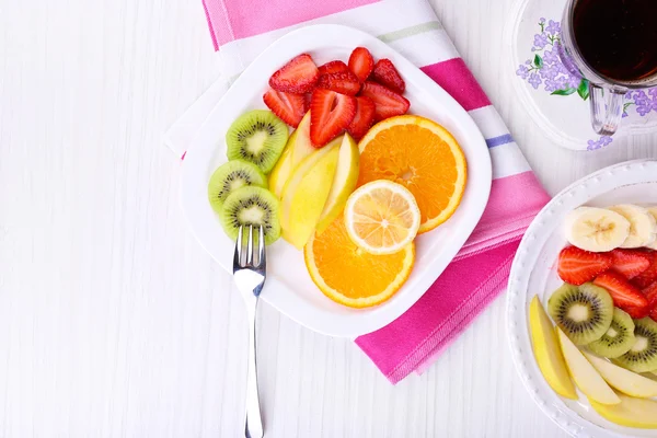 Various sliced fruits on plates on table close-up — Stock Photo, Image