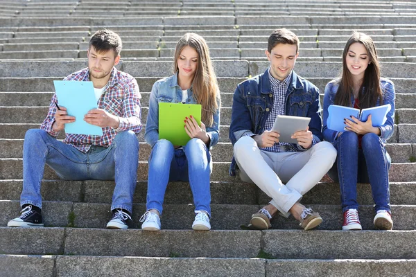 Šťastní studenti sedí na schodech v parku — Stock fotografie