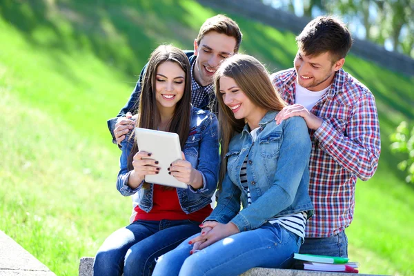 Happy students sitting in park — Stock Photo, Image
