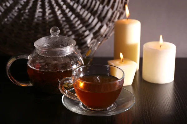 Složení s čajem ve skleněné konvici a svíčky na stole, na tmavém pozadí — Stock fotografie