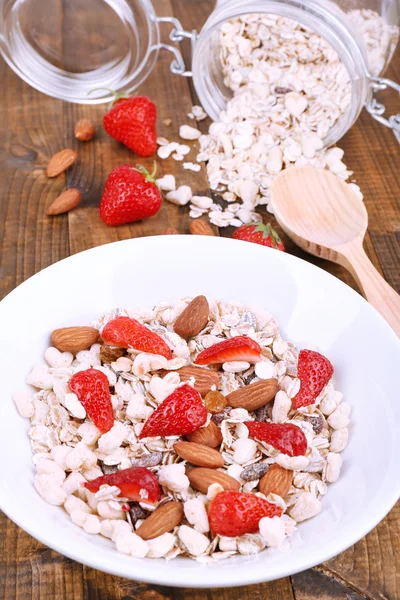 Healthy cereal with strawberry and nuts on wooden table — Stock Photo, Image