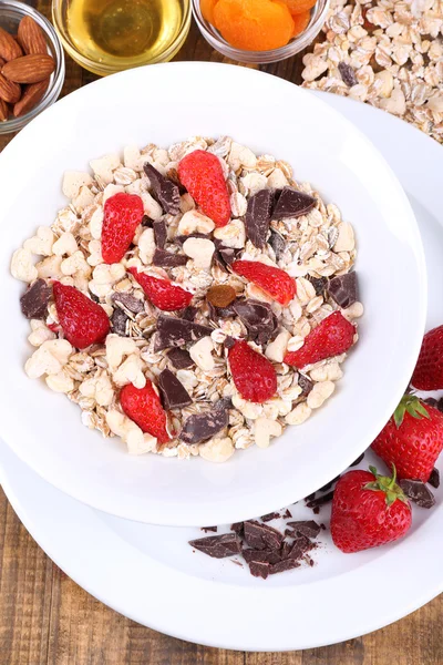 Cereales saludables en tazón con fresas y chocolate en mesa de madera — Foto de Stock