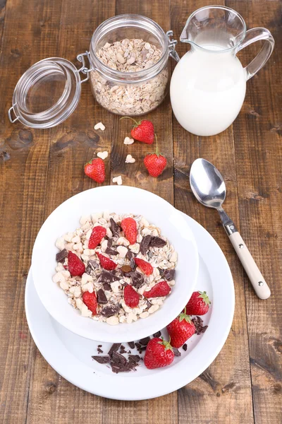 Gezonde granen in kom met aardbeien en chocolade op houten tafel — Stockfoto