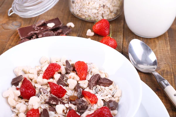 Gezonde granen in kom met aardbeien en chocolade op houten tafel — Stockfoto