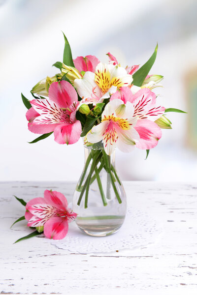 Alstroemeria flowers in vase on table on light background