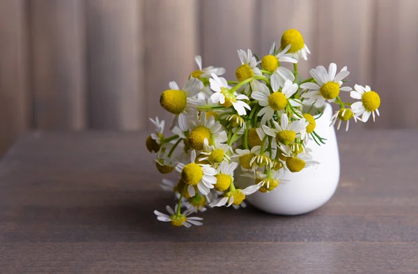 Beautiful daisies flowers in vase on table on grey background — Stock Photo, Image