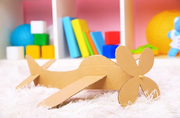 Papírové letadlo hračka v pokoji na koberci — Stock fotografie