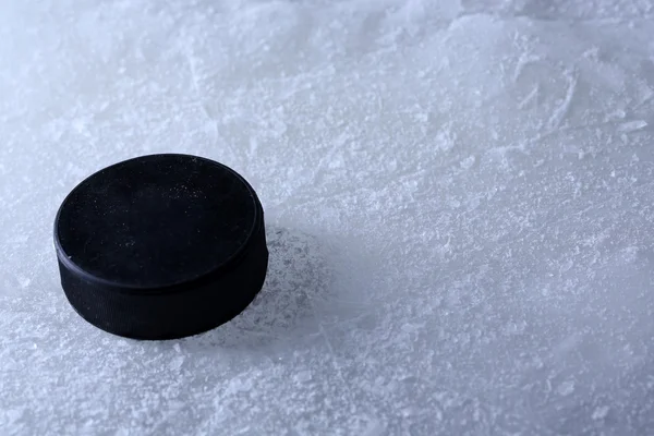 Svart hockey puck på ice rink bakgrund — Stockfoto