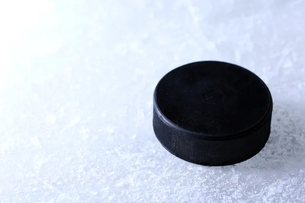 Schwarzer Eishockey-Puck auf Eisbahn Hintergrund — Stockfoto
