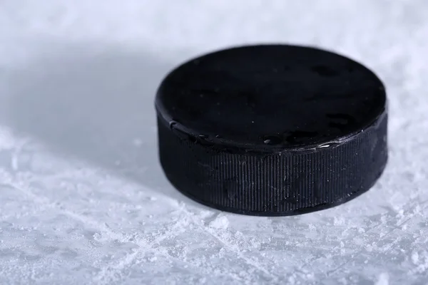 Schwarzer Eishockey-Puck auf Eisbahn Hintergrund — Stockfoto