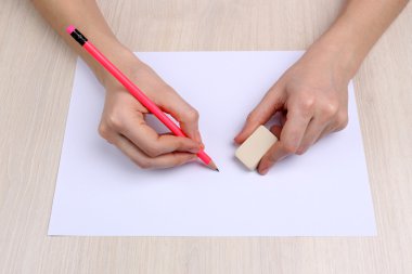 insan eli kalem kağıt ve erase kauçuk ahşap masa arka plan üzerinde yazma ile