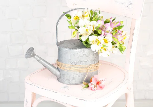 Beautiful bouquet of freesias in watering can on chair in room — Stock Photo, Image