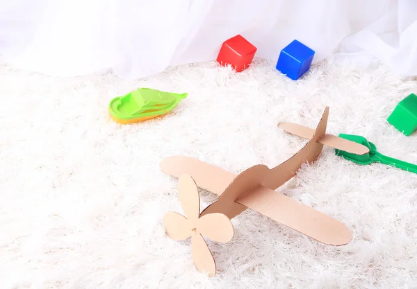 Giocattolo di carta aeroplano in camera sul tappeto — Foto Stock