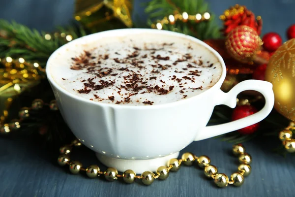 Cioccolata calda con crema in tazza di colore, sul tavolo, su sfondo decorazioni natalizie — Foto Stock