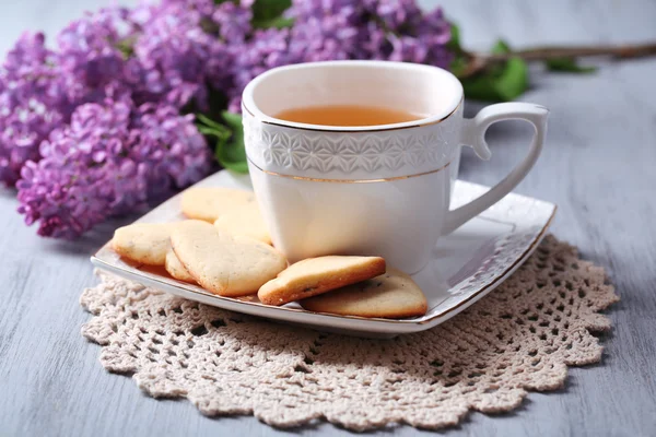 Lavender cookies and cup of tasty tea on color wooden background — Stock Photo, Image