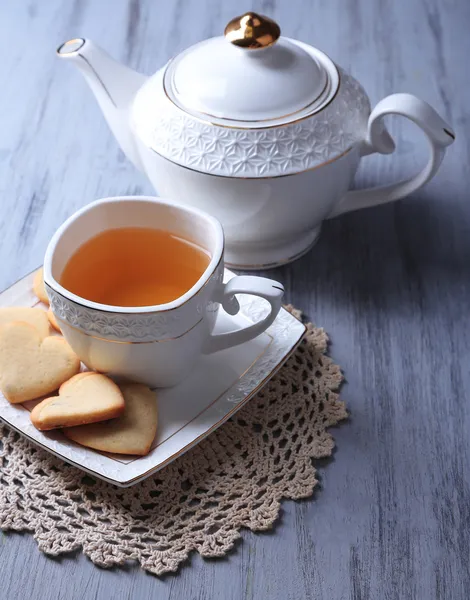 Biscoitos de lavanda e xícara de chá saboroso na cor de fundo de madeira — Fotografia de Stock