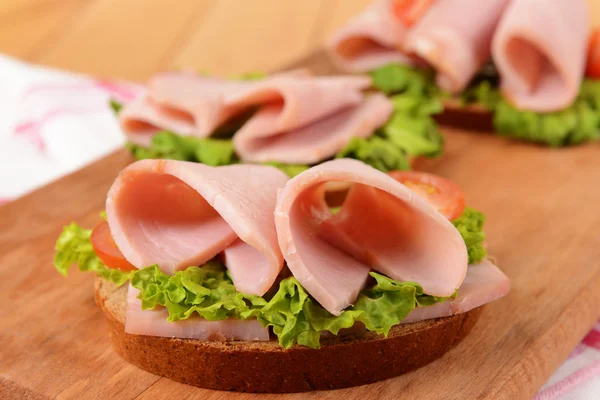 Heerlijke sandwiches met sla en ham op tafel close-up — Stockfoto