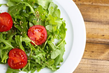 roka, domates ve susam ahşap zemin üzerinde plaka üzerinde yapılmış yeşil salata