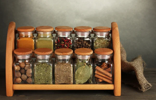Frascos con especias en el estante, en la mesa sobre fondo gris — Foto de Stock