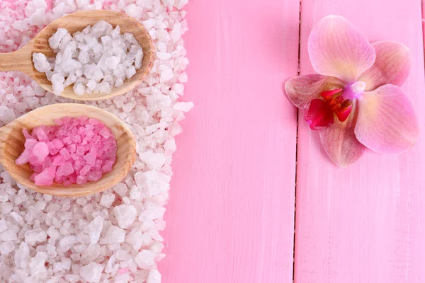 Still life with beautiful blooming orchid flower  and wooden spoons with sea salt, on color wooden background — Stock Photo, Image