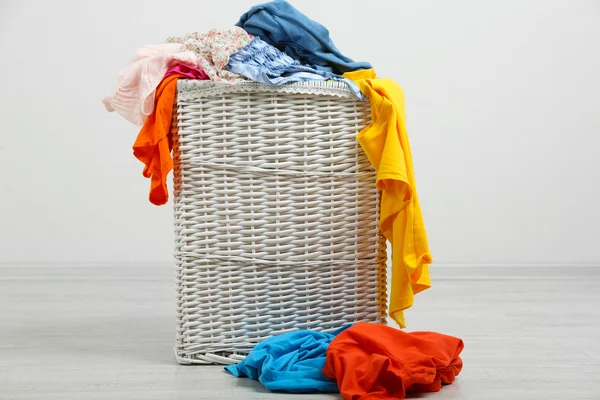 Panier à linge complet sur sol en bois sur fond gris — Photo