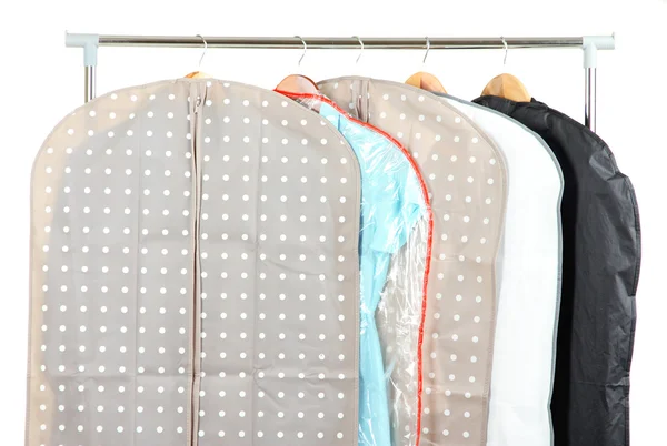 Kleidung in Etuis zur Aufbewahrung auf Kleiderbügeln, auf grauem Hintergrund — Stockfoto