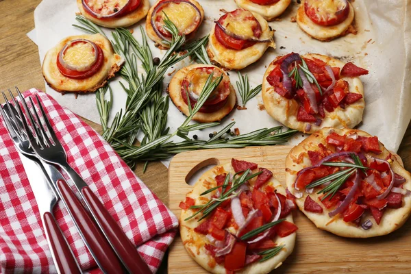 Pequeñas pizzas sobre papel de hornear de cerca —  Fotos de Stock