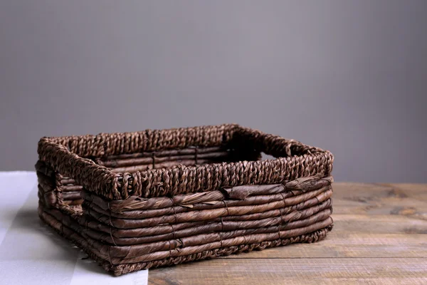 Empty wicker basket on wooden table, on dark background — Stock Photo, Image