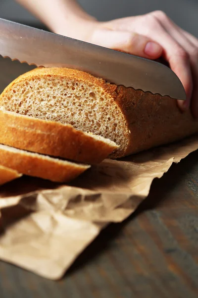 Ahşap tahtada ekmek kesen kadın elleri, yakın plan. — Stok fotoğraf