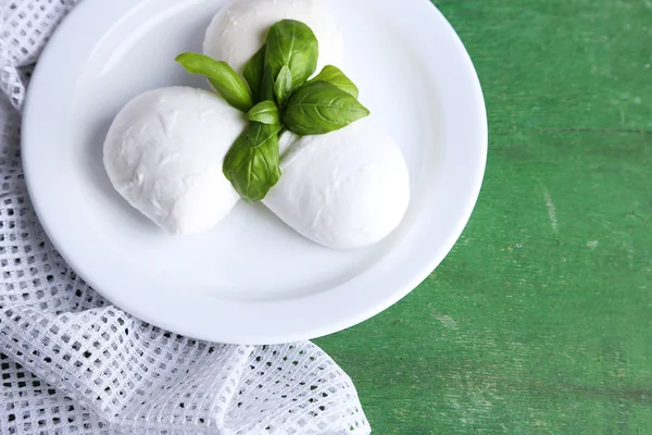 Sabroso queso mozzarella con albahaca en plato sobre fondo de madera — Foto de Stock