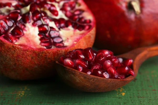 Ripe pomegranates on color wooden background — Stock Photo, Image