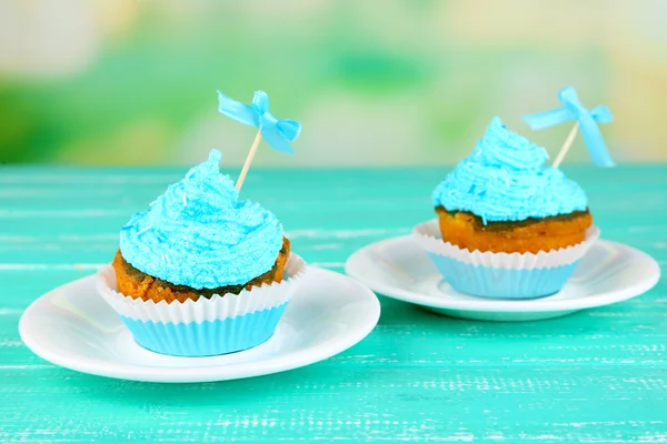青い木製テーブルの上のクリームとおいしいカップ ケーキ — ストック写真