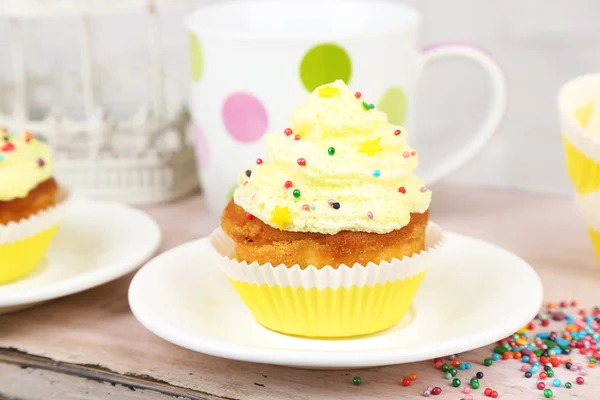 Tasty cup cakes with cream on wooden table — Stock Photo, Image