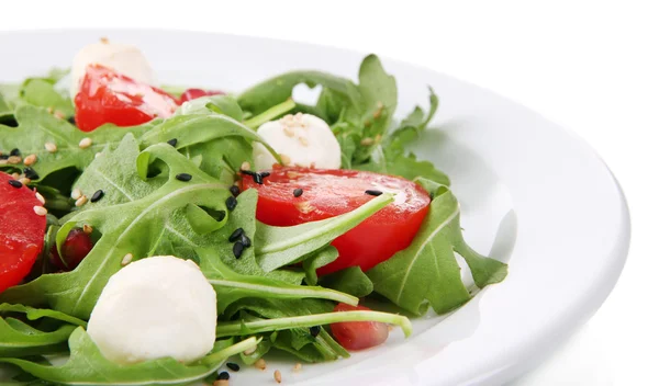 Zelený salát s rukolou, rajčaty, sýr mozzarella koule a sezam na desce, izolované na bílém — Stock fotografie