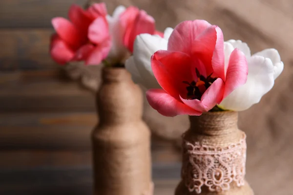 Vackra tulpaner i hink i vas på bordet på grå bakgrund — Stockfoto