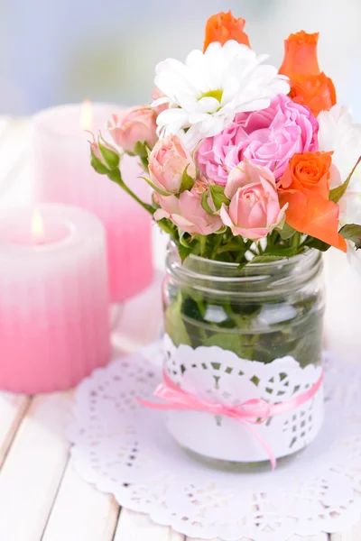 Hermoso ramo de flores brillantes en frascos en la mesa sobre fondo claro —  Fotos de Stock