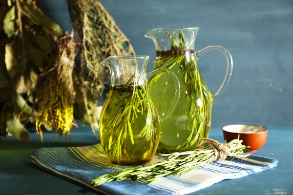 Эфирное масло с розмарином в стеклянных кувшинах, на деревянном фоне — стоковое фото