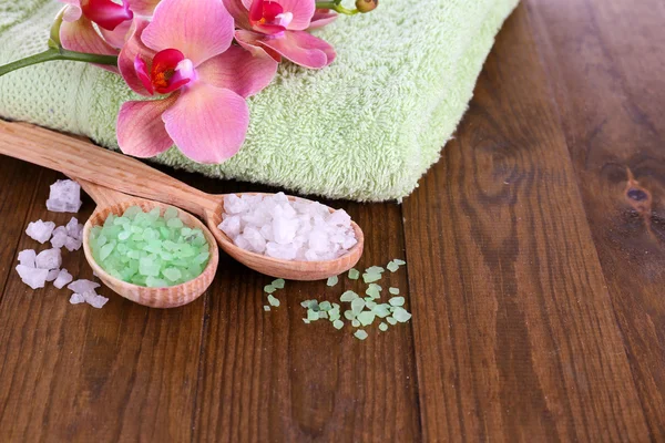 Bodegón con hermosa flor de orquídea y cucharas de madera con sal marina, sobre fondo de madera de color — Foto de Stock