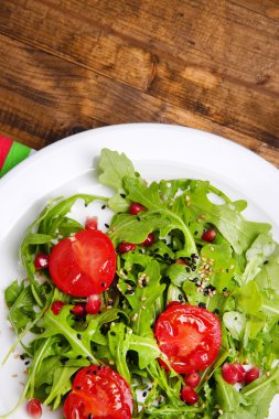 roka, domates ve susam ahşap zemin üzerinde plaka üzerinde yapılmış yeşil salata