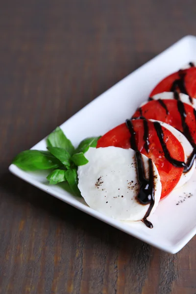 Mozarella peyniri, domates ve fesleğen ahşap masa arka plaka Caprese salatası — Stok fotoğraf