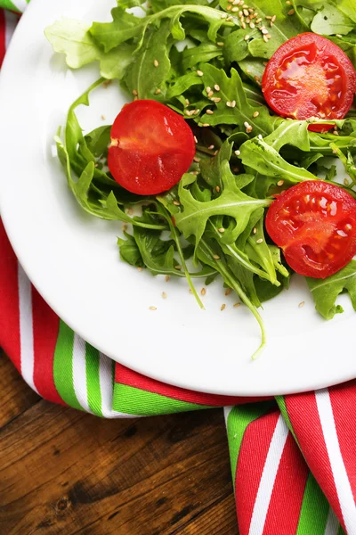 ルッコラ、トマト、プレート、木製の背景上にゴマを使ったグリーン サラダ — ストック写真
