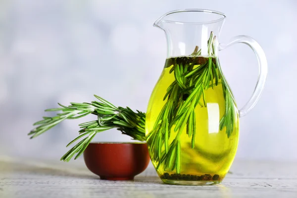 Ätherisches Öl mit Rosmarin im Glaskrug, auf hellem Hintergrund — Stockfoto