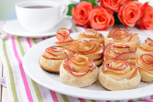 Tasty bladerdeeg met apple vormige rozen op plaat op tabel close-up — Stockfoto