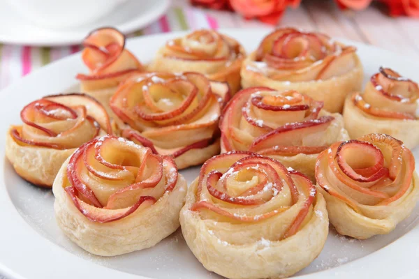 Вкусное слоеное тесто с розами в форме яблока на тарелке на столе крупным планом — стоковое фото