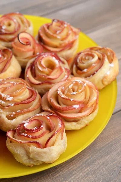 Tasty bladerdeeg met apple vormige rozen op plaat op tabel close-up — Stockfoto