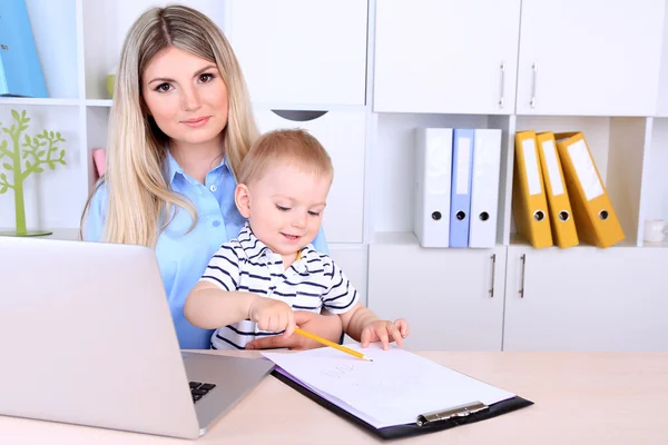 Mulher bonita com bebê trabalhando em casa — Fotografia de Stock